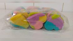 four colorful cookies wrapped in plastic on a counter