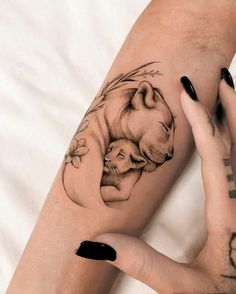 a woman with black nails and tattoos on her arm is holding a baby polar bear