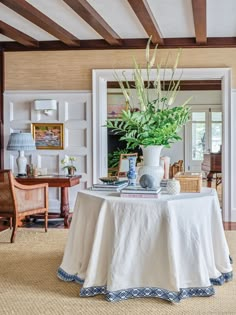 there is a table with a white cloth on it and a potted plant in the center