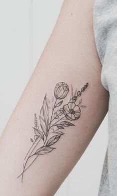 a black and white photo of a flower tattoo on the right arm, with a feather