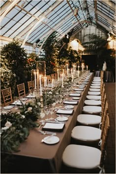 a long table is set with white plates and place settings