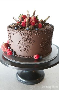 a chocolate cake with berries and leaves on top