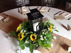 a table with a lantern and sunflowers on it