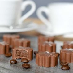 several pieces of chocolate sitting on top of a table next to coffee beans and a cup