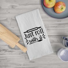 a tea towel that says just roll with it next to two apples