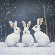 two white rabbits sitting in the snow with trees and snowflakes behind them on a dark night