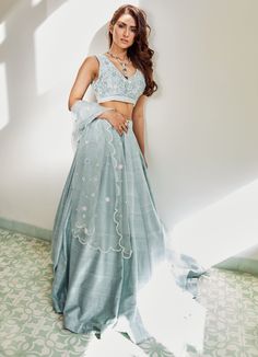 Luxurious Raw Silk Kali Lehenga in a sea blue colour teamed with a handcrafted blouse which features hand embroidered flowers and butterflies in pearls and silk thread work in sea blue, pastel pink and sage green hues. The blouse is a a product of 60 hours with every flower and butterfly exquisitely detailed. Completed with a signature organza scalloped dupatta Can be customised in any colour Composition: Lehenga and Blouse - Raw Silk Dupatta - Organza All products can be customised for sleeves, Blue Silk Embellished Lehenga, Blue Sets With Pearl Embroidery For Reception, Light Blue Sets With Intricate Embroidery, Traditional Blue Sets With Pearl Embroidery, Spring Silk Lehenga With Floral Embroidery, Silk Lehenga With Pearl Embroidery For Reception, Festive Blue Sets With Pearl Embroidery, Blue Embellished Raw Silk Sets, Embellished Blue Raw Silk Set