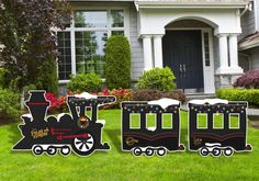 three wooden train decorations in front of a house