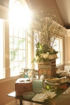 a room filled with lots of furniture and flowers on top of a window sill