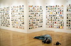 a man laying on the floor in front of a wall with bookshelves behind him