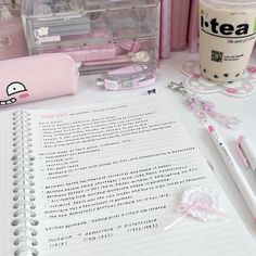 a table topped with lots of pink items next to a cup of coffee and pen