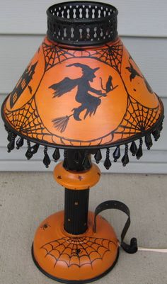 an orange lamp with a black spider web design on it and a pumpkin colored shade