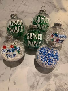 four glass christmas ornaments with the words grinch poop and snowman pop on them