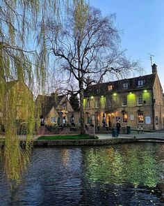 a river running through a small town next to a tall building with lights on it