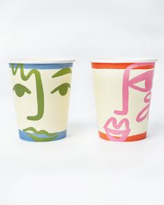 two cups with faces painted on them sitting next to each other in front of a white background