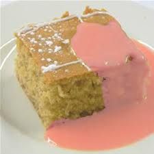 a piece of cake on a plate with pink sauce and white icing around it