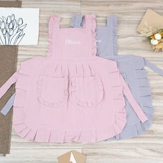 three pieces of clothing sitting on top of a wooden floor next to flowers and envelopes