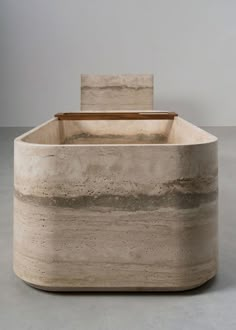 a large stone container sitting on top of a cement floor next to a white wall