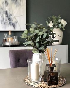 a table topped with candles and vases filled with greenery