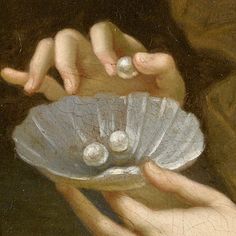 a close up of a person holding a seashell in their hands with pearls on it