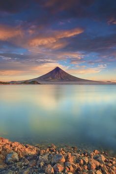 an image of a mountain that is in the distance with water and rocks around it