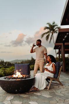 a man and woman sitting around a fire pit