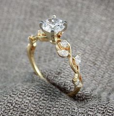 a close up view of a diamond ring on a gray cloth with the background textured