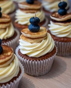 cupcakes with white frosting and blueberries on top are arranged in rows