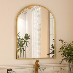 a bathroom sink with a mirror above it next to a vase and potted plant