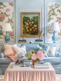 a living room filled with blue couches covered in pink and green flowers next to a painting