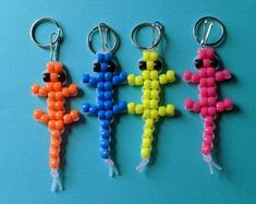 four key chains with different colored beads hanging from each one on a blue surface,