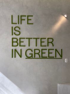 the words life is better in green are displayed on a wall behind a stair case