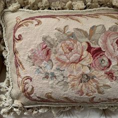 an embroidered pillow with tassels and flowers on the bottom is sitting on a chair