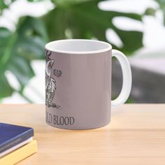 a white coffee mug sitting on top of a wooden table next to a blue book