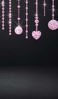 some pink and white ornaments hanging from a black ceiling with lights in the dark behind them