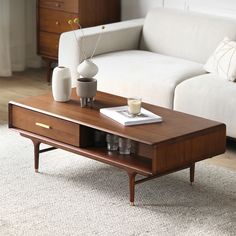 a coffee table with two vases on it in front of a white couch and rug