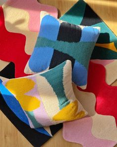 four different colored pillows sitting on top of a wooden table