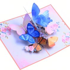 there are many colorful butterflies on this greeting card that is folded in pink and blue