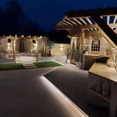 an outdoor living area lit up at night with lights on the roof and seating areas