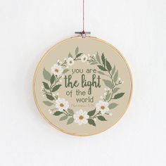 a cross stitch hoop hanging on a wall with the words, you are the light at the world