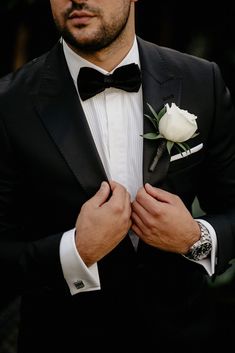 a man in a tuxedo adjusts his bow tie