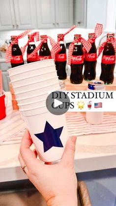 a person holding up a stack of cups with red, white and blue decorations on them