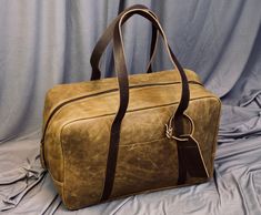 a brown leather bag sitting on top of a bed