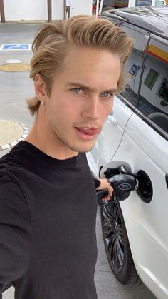 a young man standing next to a white car