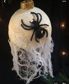 a white ornament with a black spider on it's head, hanging from a christmas tree