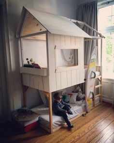 a young boy sitting on top of a wooden bunk bed next to a surfboard