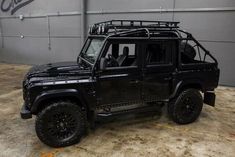 a black land rover is parked in front of a building with graffiti on the wall