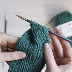 someone is knitting something green on the table