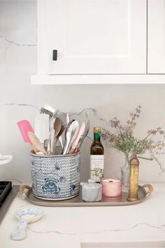 kitchen utensils in a blue and white container on a counter top with flowers