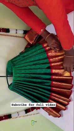 a woman is holding a green and red fan in her hand while standing on the floor